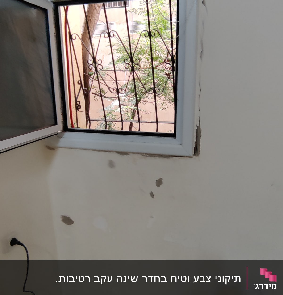 קיר עם חורים ותיקוני טיח ליד חלון פתוח